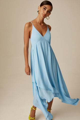A female is wearing a midi cami dress with a high low hemline.